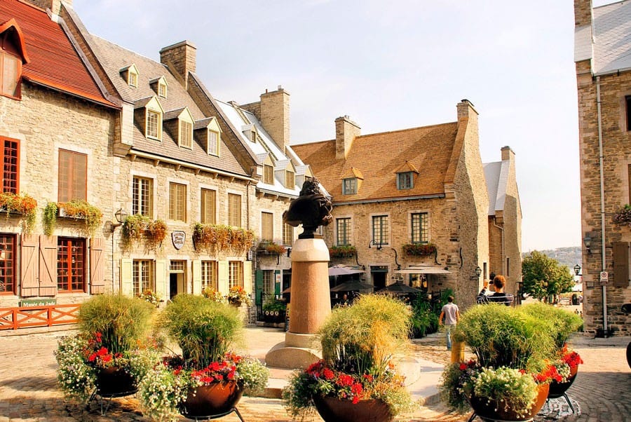 qué ver en Canadá este Plaza con casitas de color marrón y plantas con flores rojas en la ciudad de Québec en Canadá